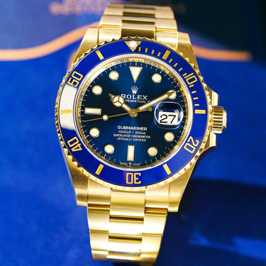 Solid Gold Rolex Submariner with blue dial and bezel. Shown stood against blue felt background.
